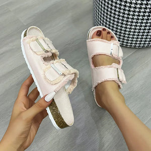 Denim frayed-edge buckle slides in blush pink with cork soles.
