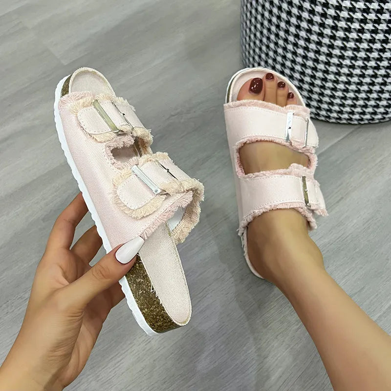 Denim frayed-edge buckle slides in blush pink with cork soles.
