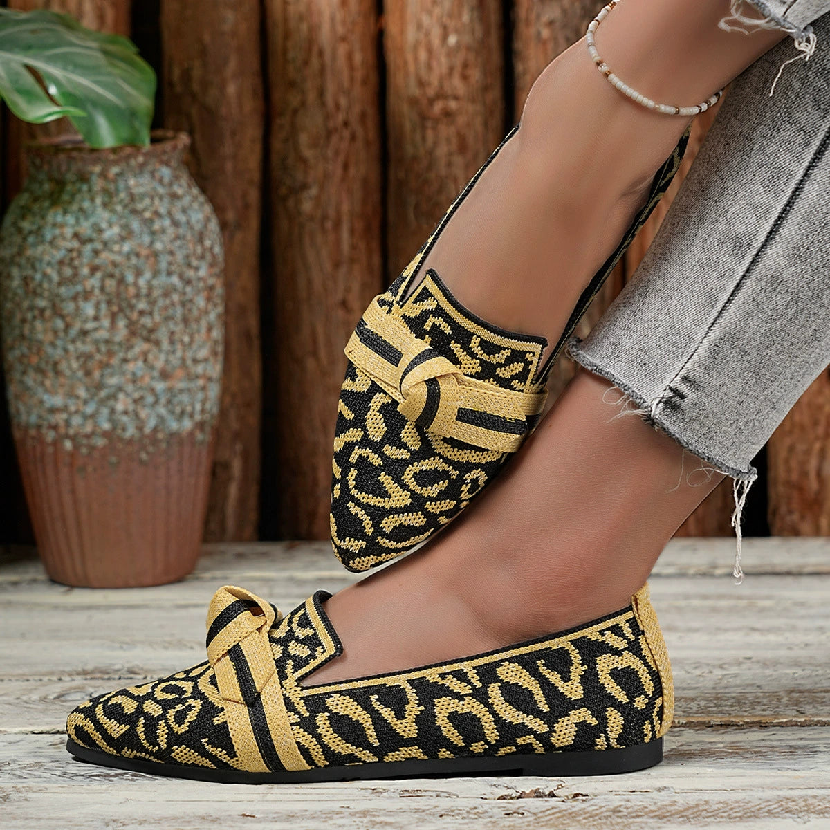 Knot detail point toe slip-ons in yellow and black abstract print knit with a comfortable fit.