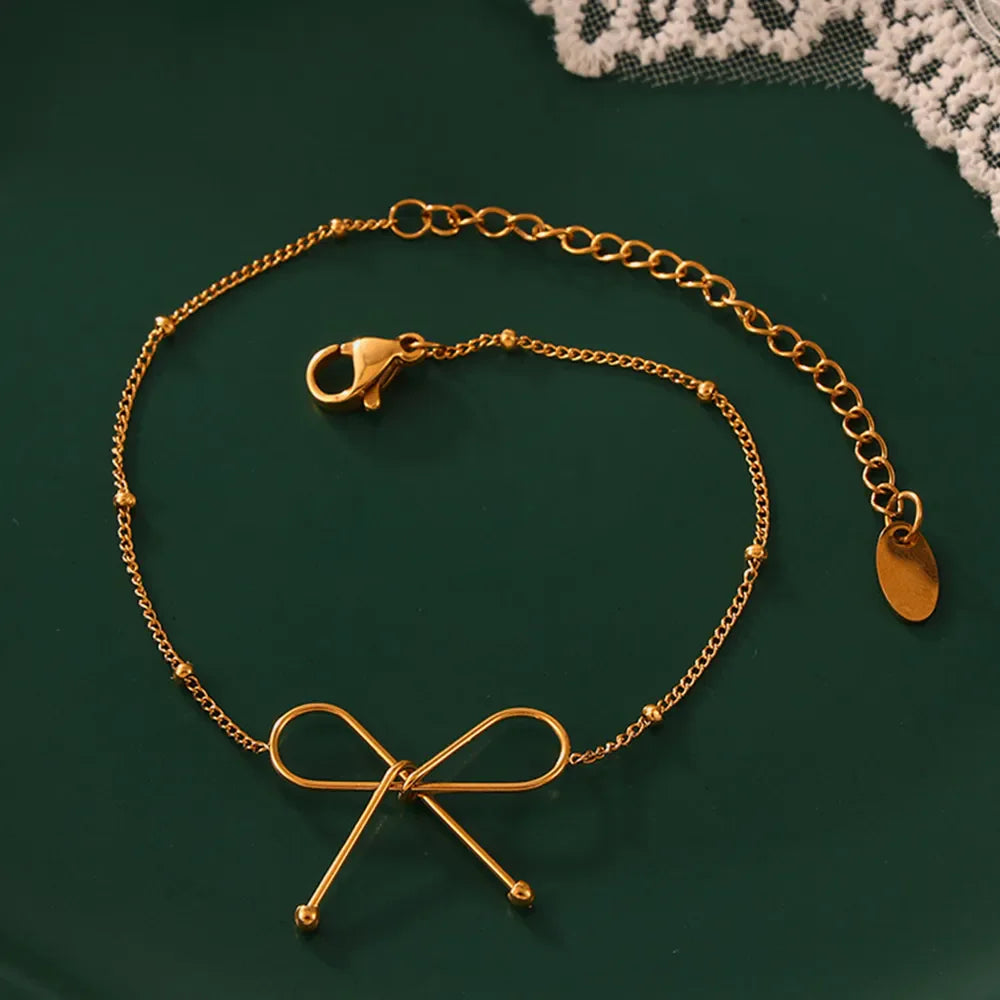 Gold delicate bow silhouette bracelet with beaded chain and lobster clasp.