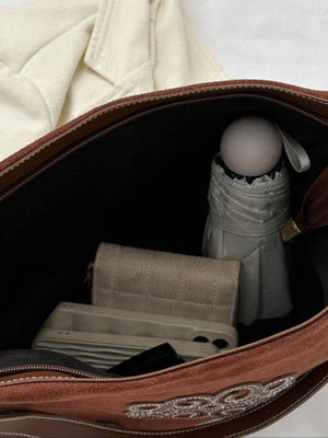 Suede hobo bag interior view showing wallet, phone, and umbrella.