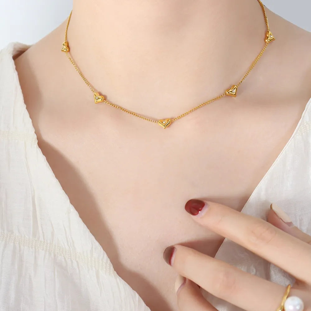 Gold chain necklace with small heart charms and zirconia accents