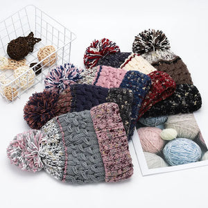 Textured cable knit beanies with pompom details in assorted colors.