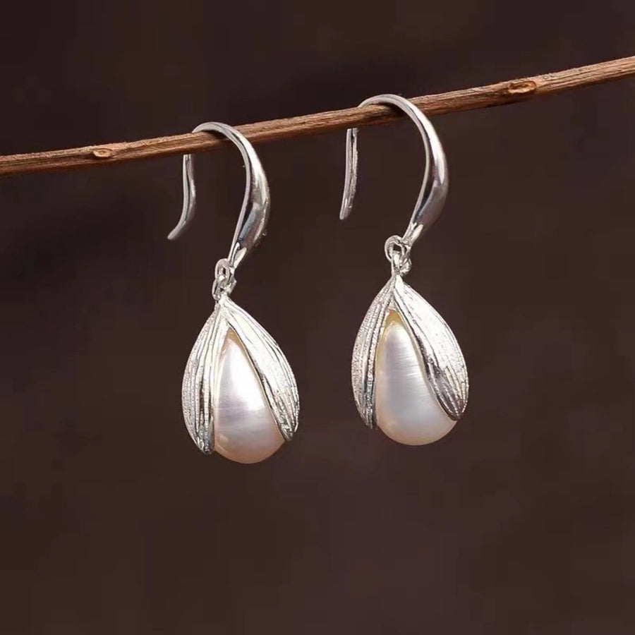 Lustrous pearl drop earrings with silver leaf-shaped settings.
