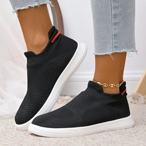 Black knit slip-on sneakers with red stripe detail and white soles.