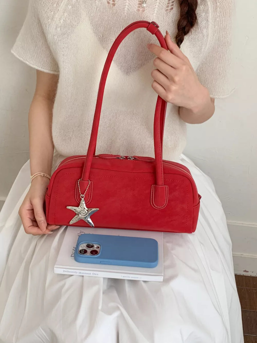 Red shoulder bag with star charm and double zipper closure.