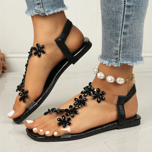 Black floral embellished PVC sandals with clear straps and elastic heel band.