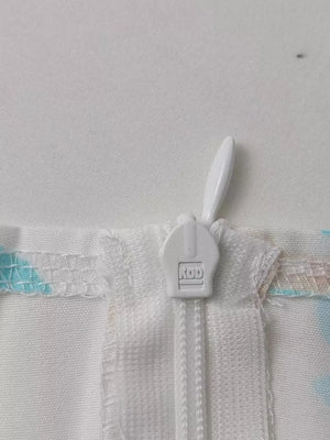 Floral maxi dress detail showing white zipper and pastel floral print.