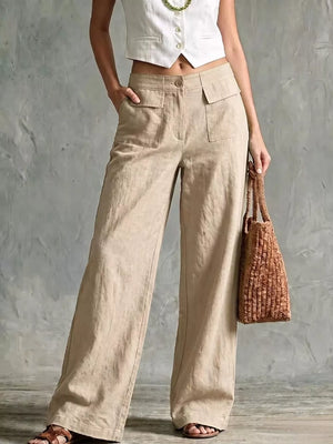 Linen wide-leg pants in beige with flap pockets and a button closure, styled with a white vest and woven bag.