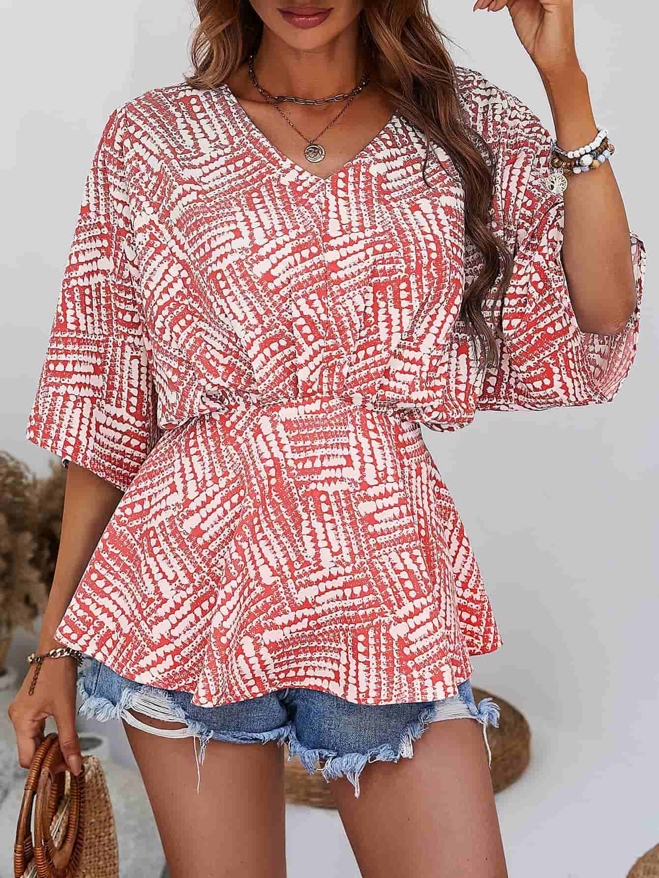 Abstract print cinched waist blouse in scarlet and white with V-neck and short sleeves.