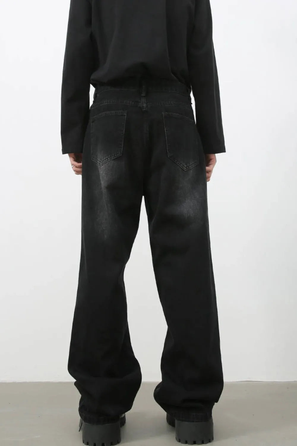 Faded black baggy denim trousers with a relaxed fit and distressed details.