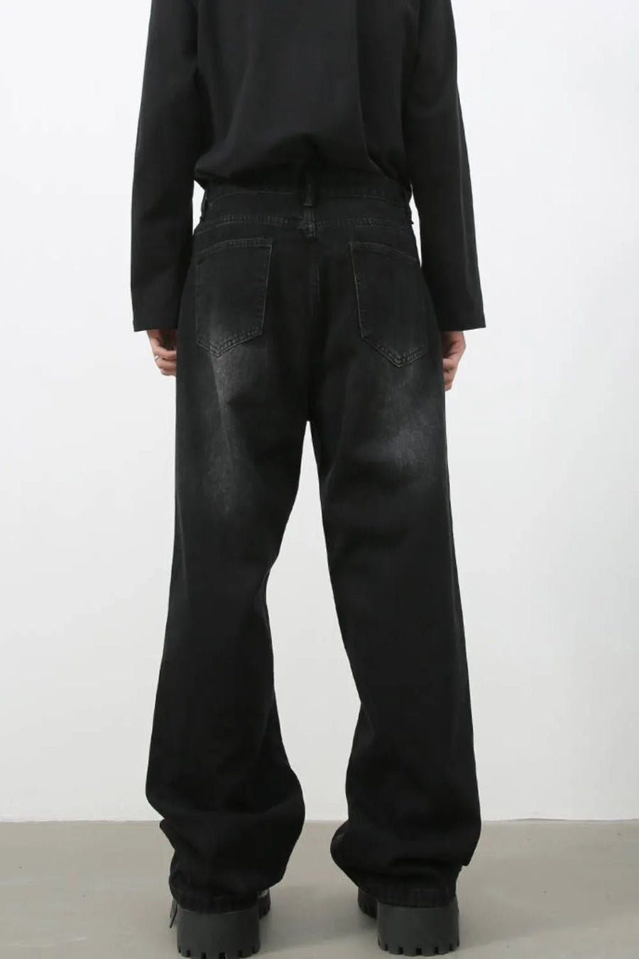 Faded black baggy denim trousers with a relaxed fit and distressed details.