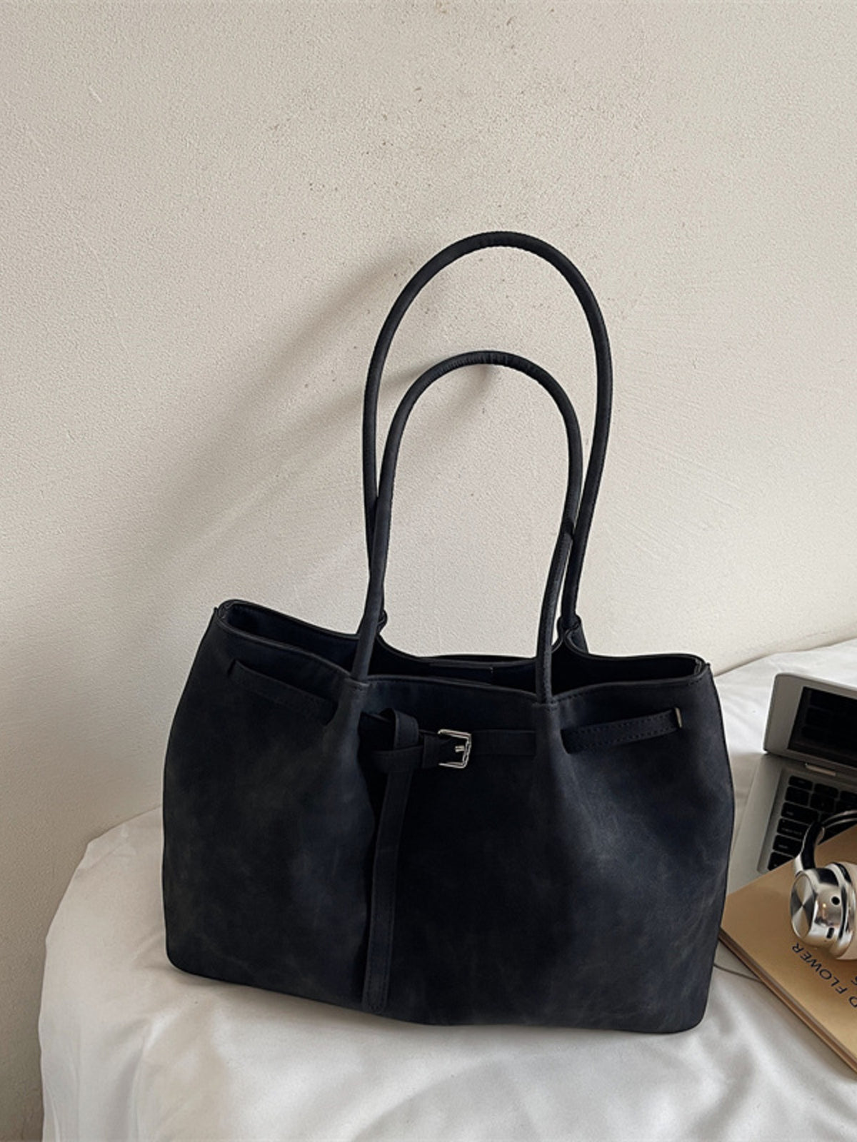 Black suede shoulder bag with buckle accent and decorative strap