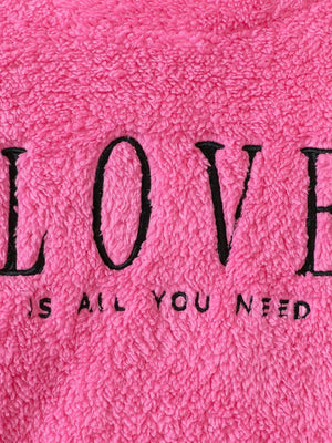 Fuzzy hot pink sweatshirt with black embroidered "LOVE IS ALL YOU NEED" text.