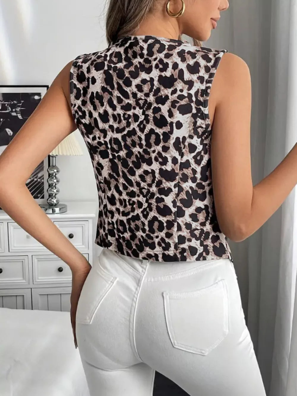 Chic leopard print sleeveless vest coat with a mock neck, worn with white jeans.