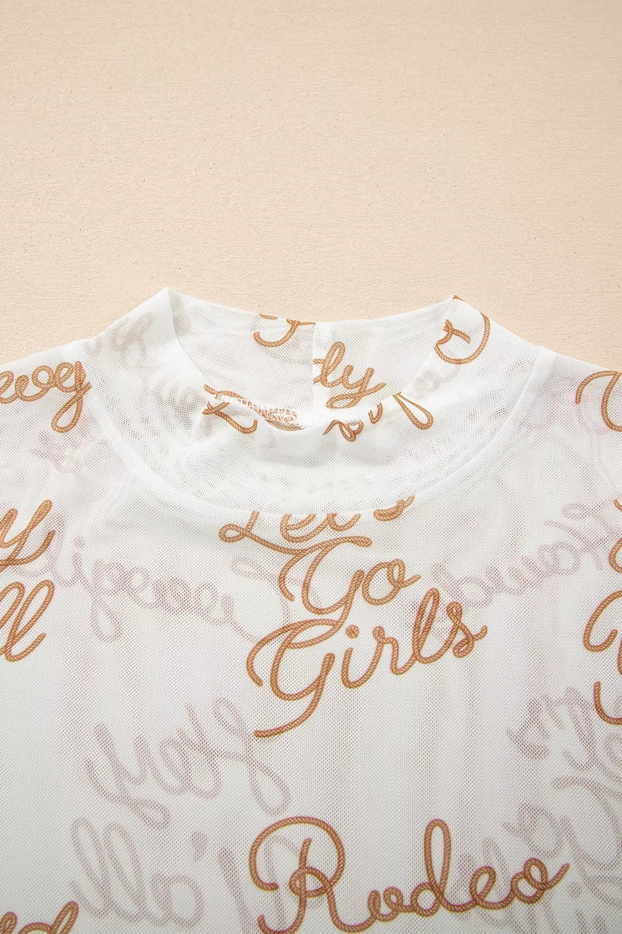 White sheer high-neck shirt with allover gold script pattern and text details.