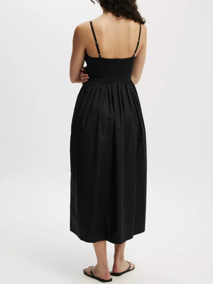 Black midi dress with adjustable straps, defined waist, and full skirt with pockets.