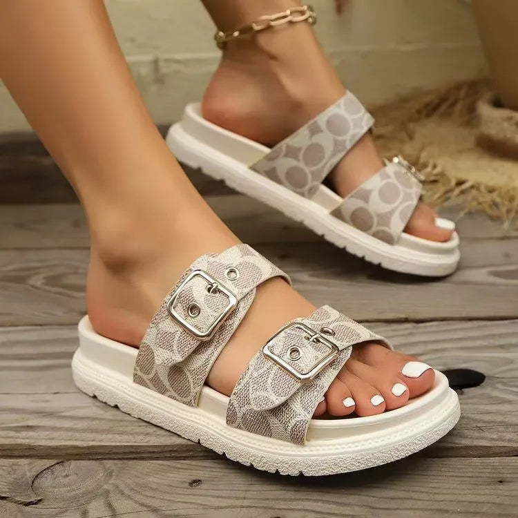Double strap logo slides in beige with buckle detail and white pedicure.