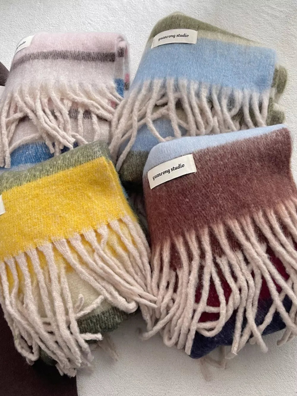Plush multi-patterned scarf with fringe in pink, yellow, green, and brown colorways.