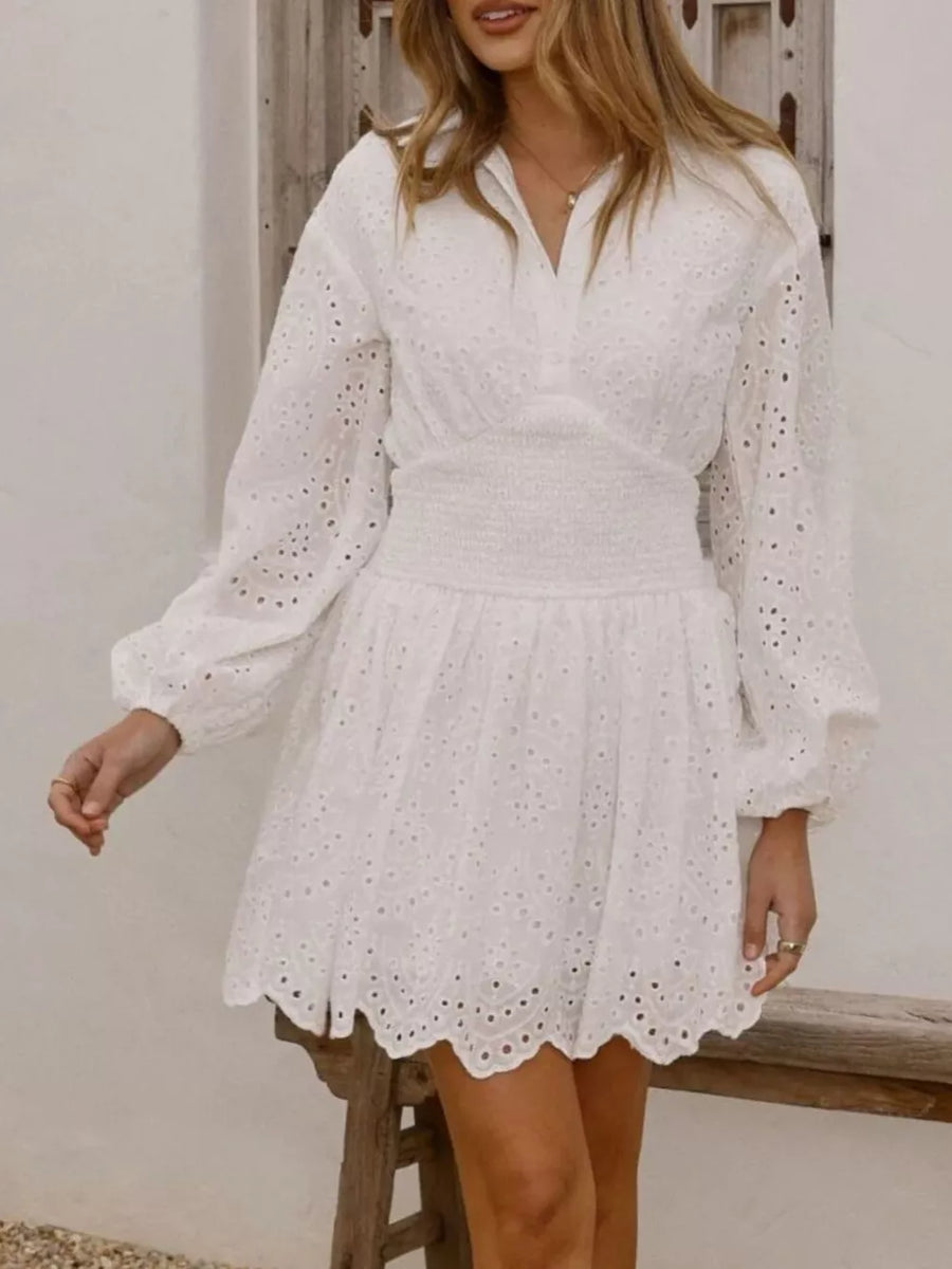 White eyelet mini dress with balloon sleeves and smocked waist.