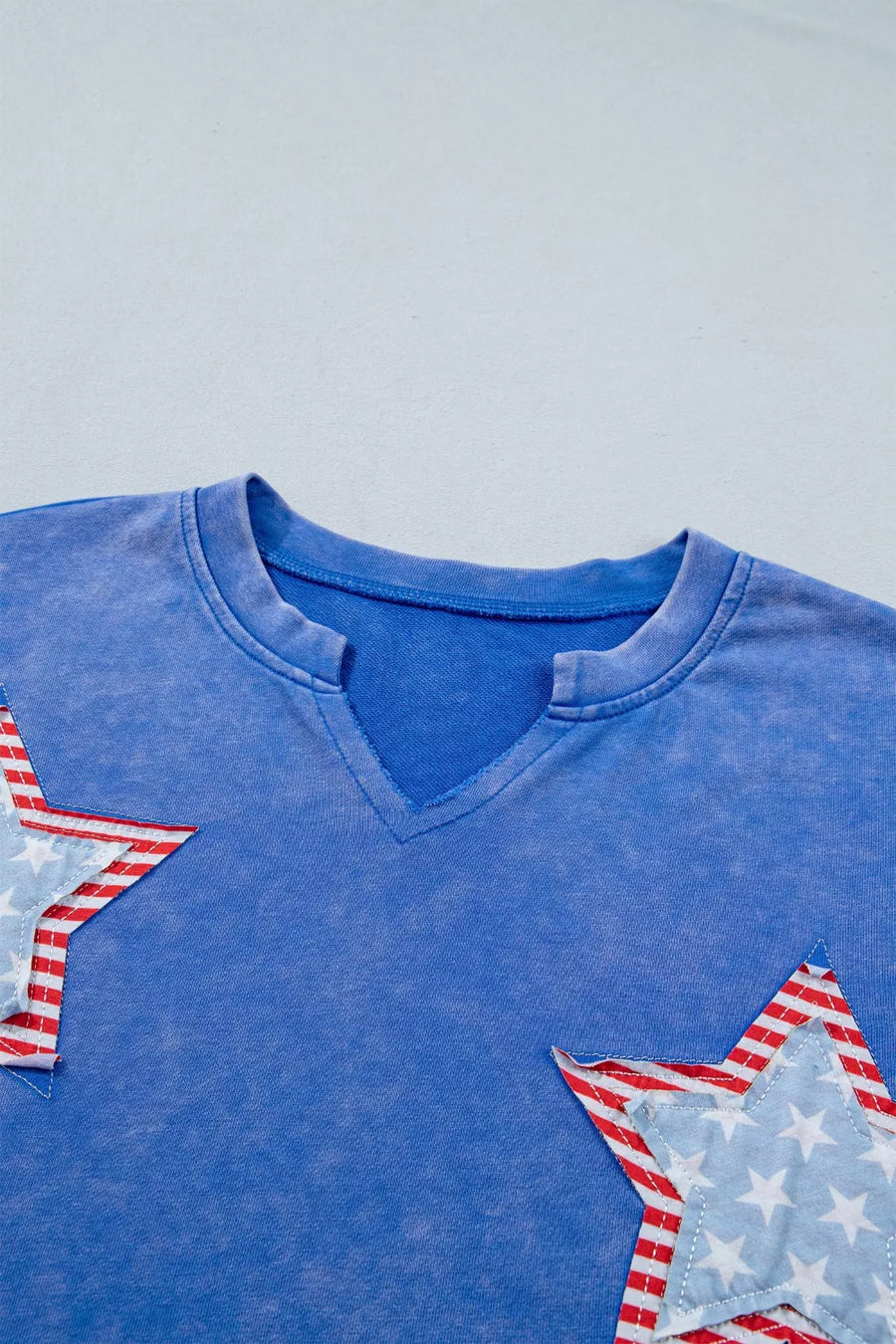 Blue cotton t-shirt with notched neck and patriotic star appliqués.
