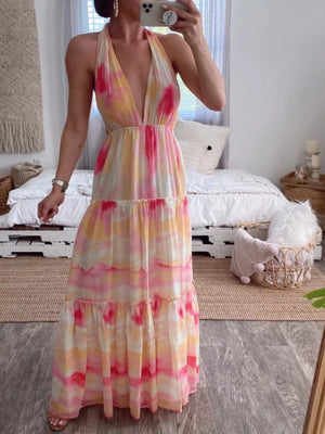 Vibrant tie-dye maxi dress with halter neckline and tiered skirt in pink, yellow, and white.