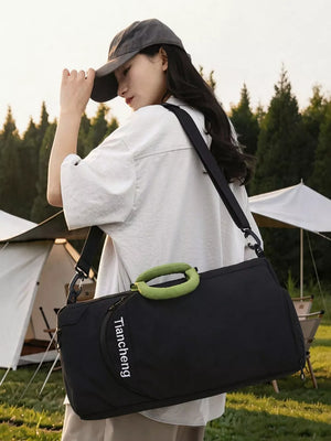 Black duffel bag with green handle and white text detail, worn crossbody.