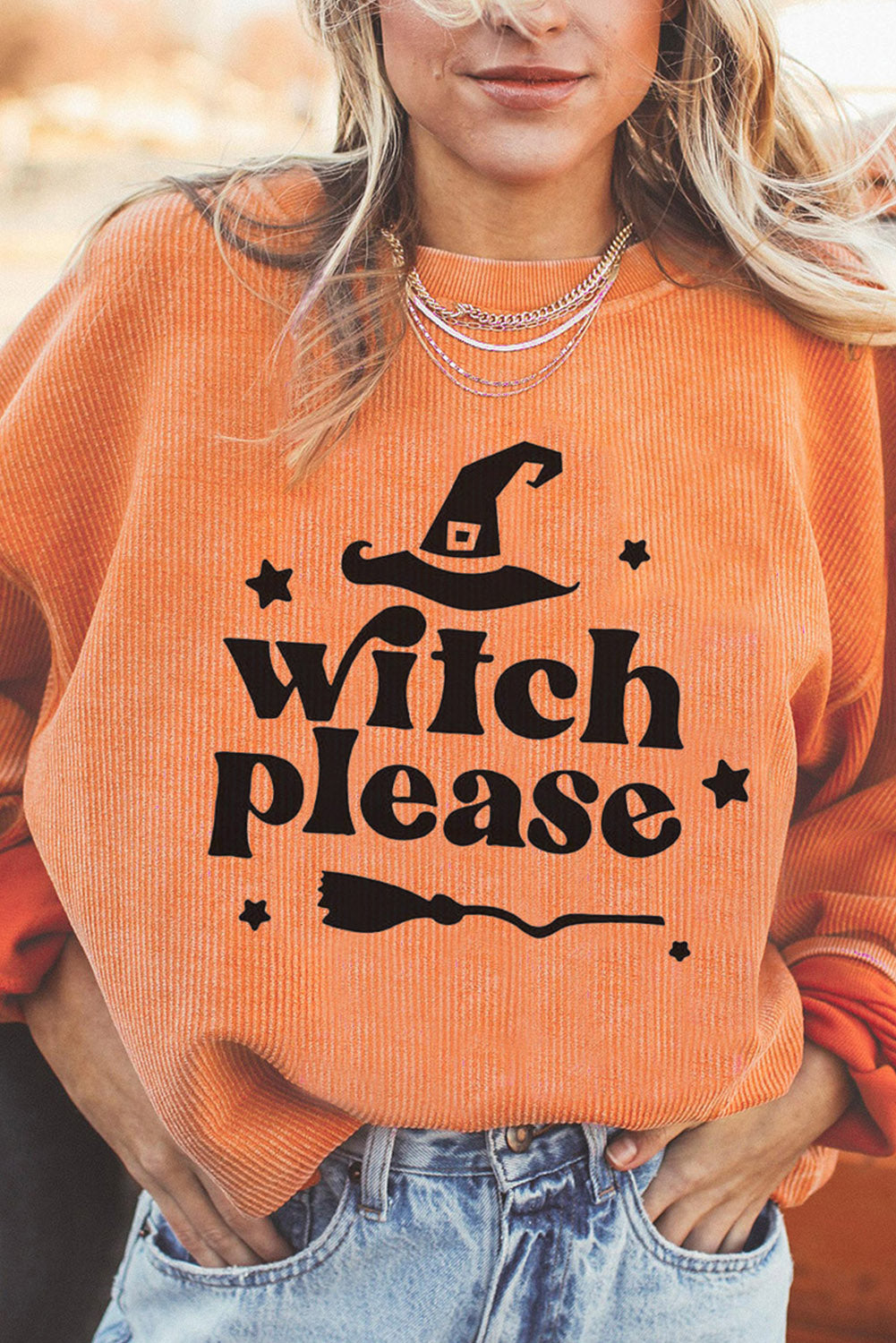 Corded orange sweatshirt with Witch Please graphic, witch hat, broom, and stars.