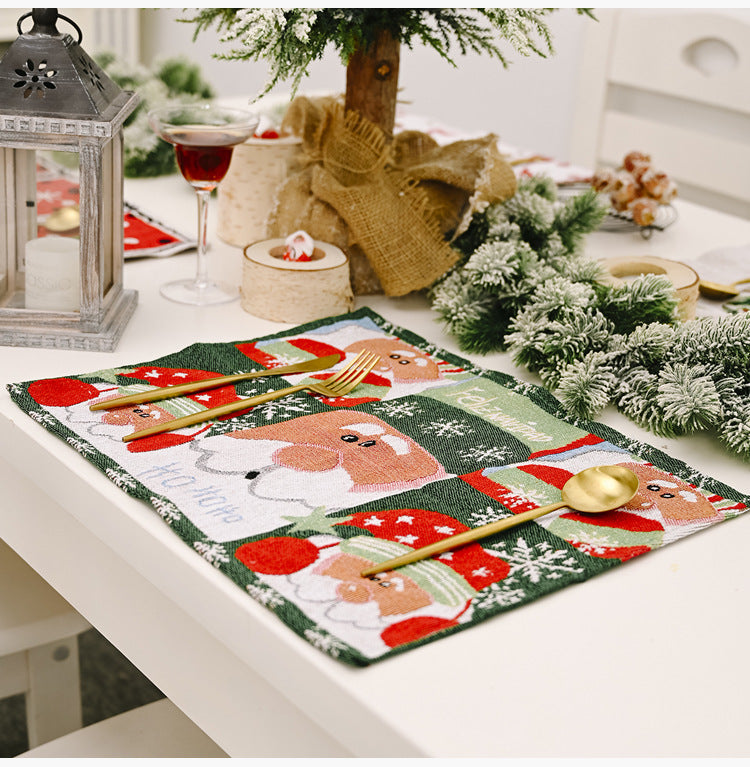 Embroidered Christmas placemat with Santa Claus scenes, gold cutlery.