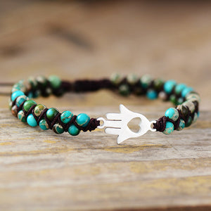 Turquoise bead bracelet with Hamsa hand charm and heart cutout detail.