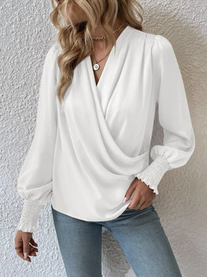 White ruched surplice blouse with V-neck, long bishop sleeves, and smocked cuffs.