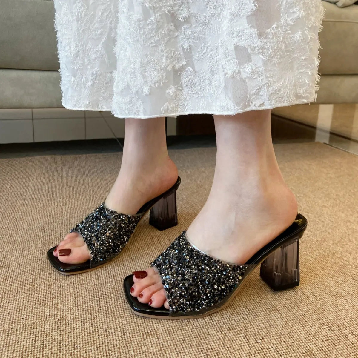 Black glitter embellished lucite heel mules with open square toe.