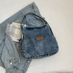 Denim hobo bag in medium wash with leatherette patch and adjustable strap.