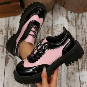 Pink and black patent leather brogue loafers with platform sole and scalloped trim.