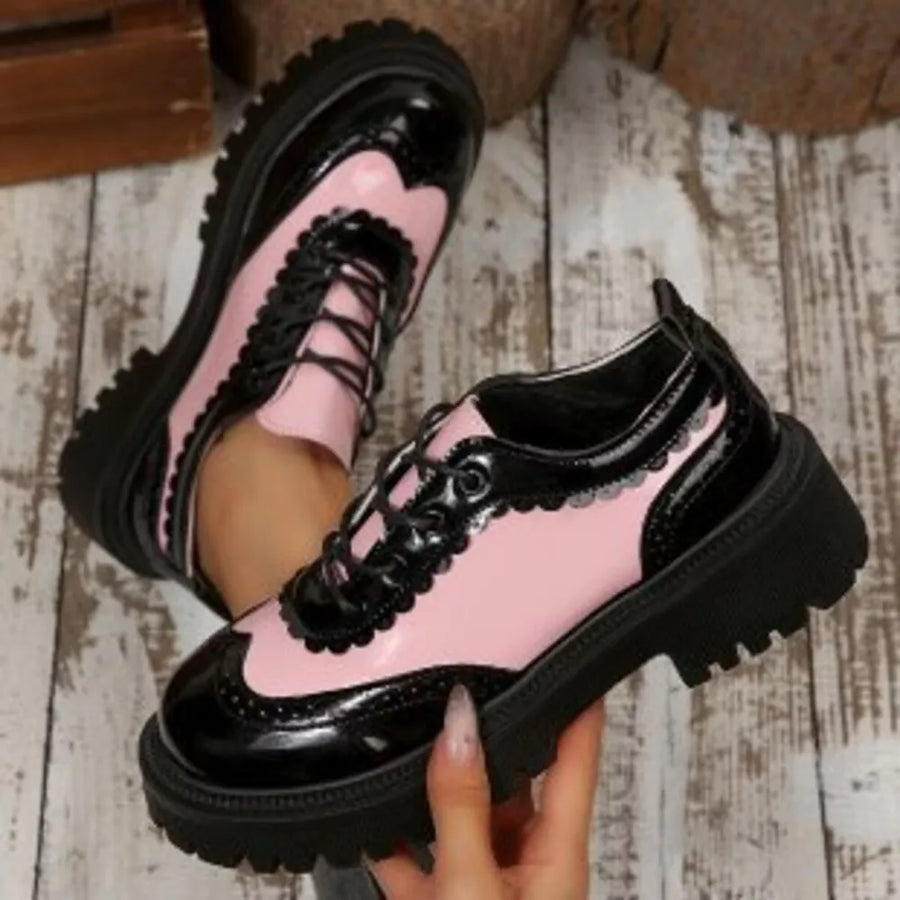 Pink and black patent leather brogue loafers with platform sole and scalloped trim.