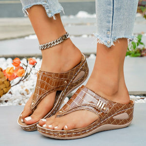 Brown crocodile-embossed wedge thong sandals with gold buckle detail.