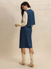 Peacock blue suede vest and skirt set with contrast stitching, worn over a cream sweater.