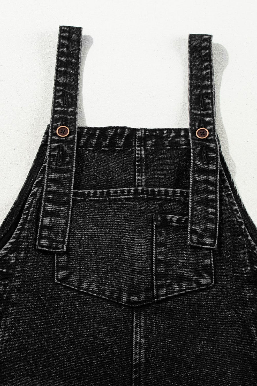 Black denim culotte overalls with distressed details and button straps.