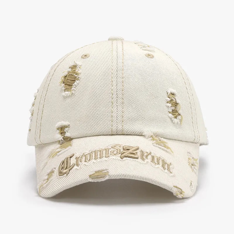 Distressed baseball cap in cream with gold embroidery and ripped details.