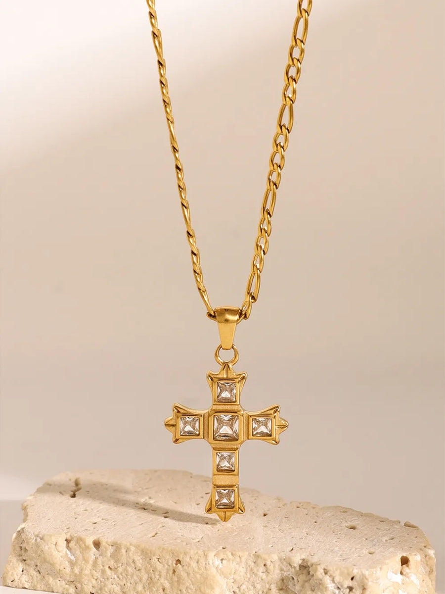 Gold cross pendant necklace with clear cubic zirconia stones on a figaro chain.