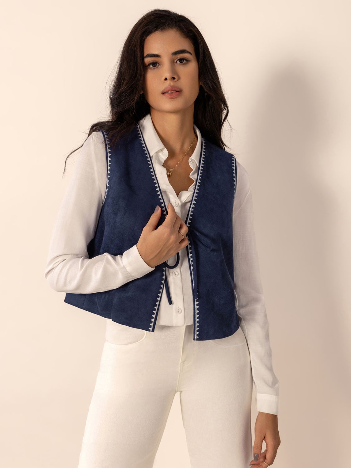 Dark blue suede-effect vest with white stitch trim and tie closure.