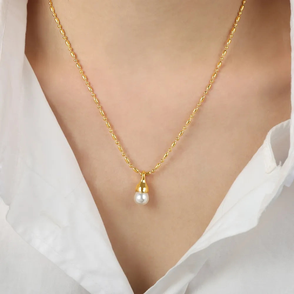 Gold chain necklace with a single pearl drop pendant and a gold cap.
