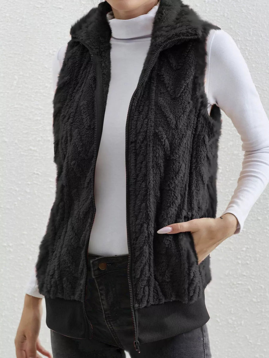 Black faux fur zip-up vest with chevron pattern and pockets.