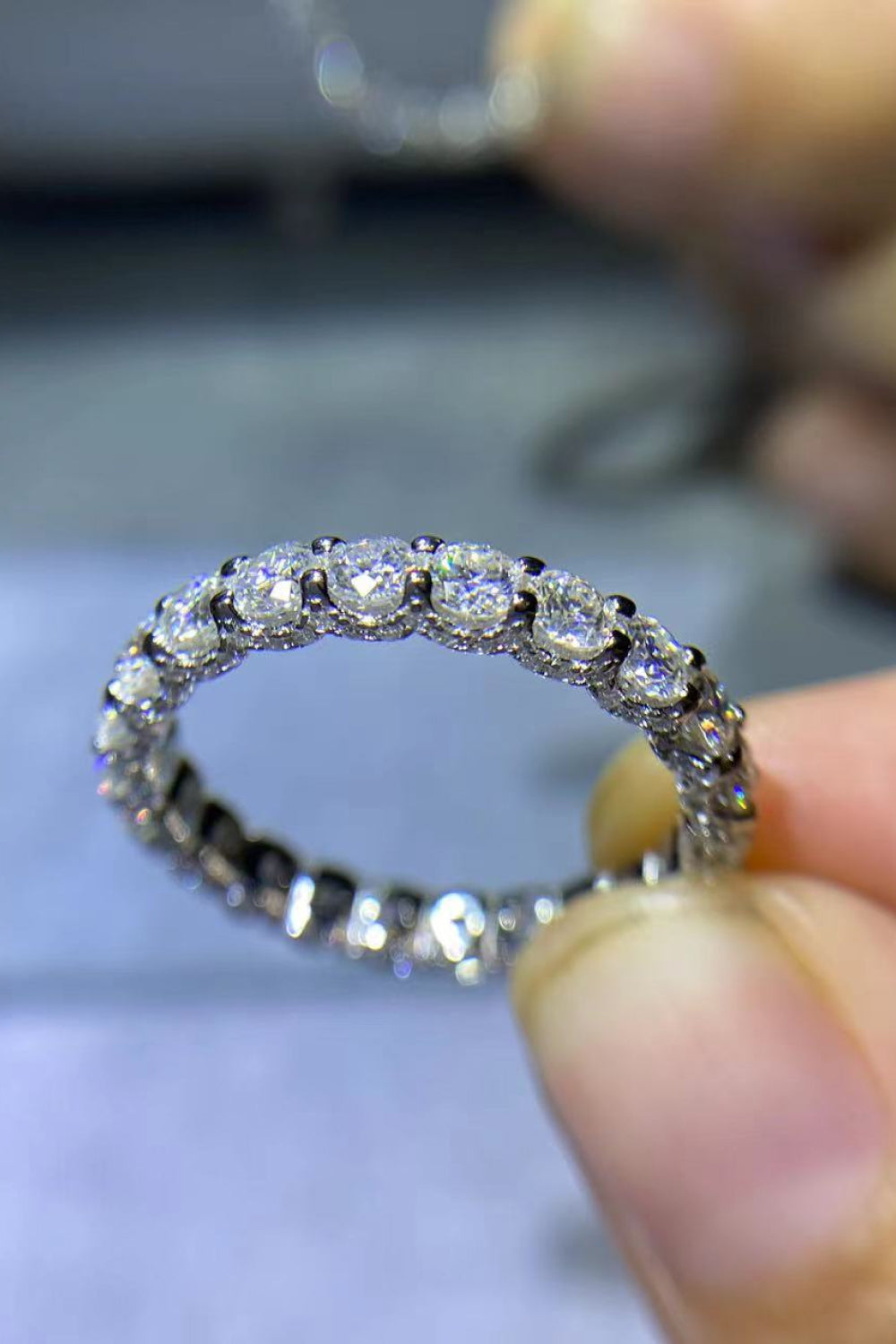 Silver eternity band ring with round moissanite stones.