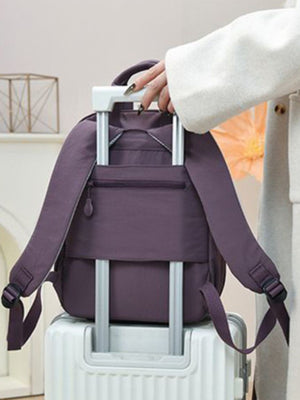 Purple mini Oxford cloth backpack with zippered pocket and adjustable straps on luggage.