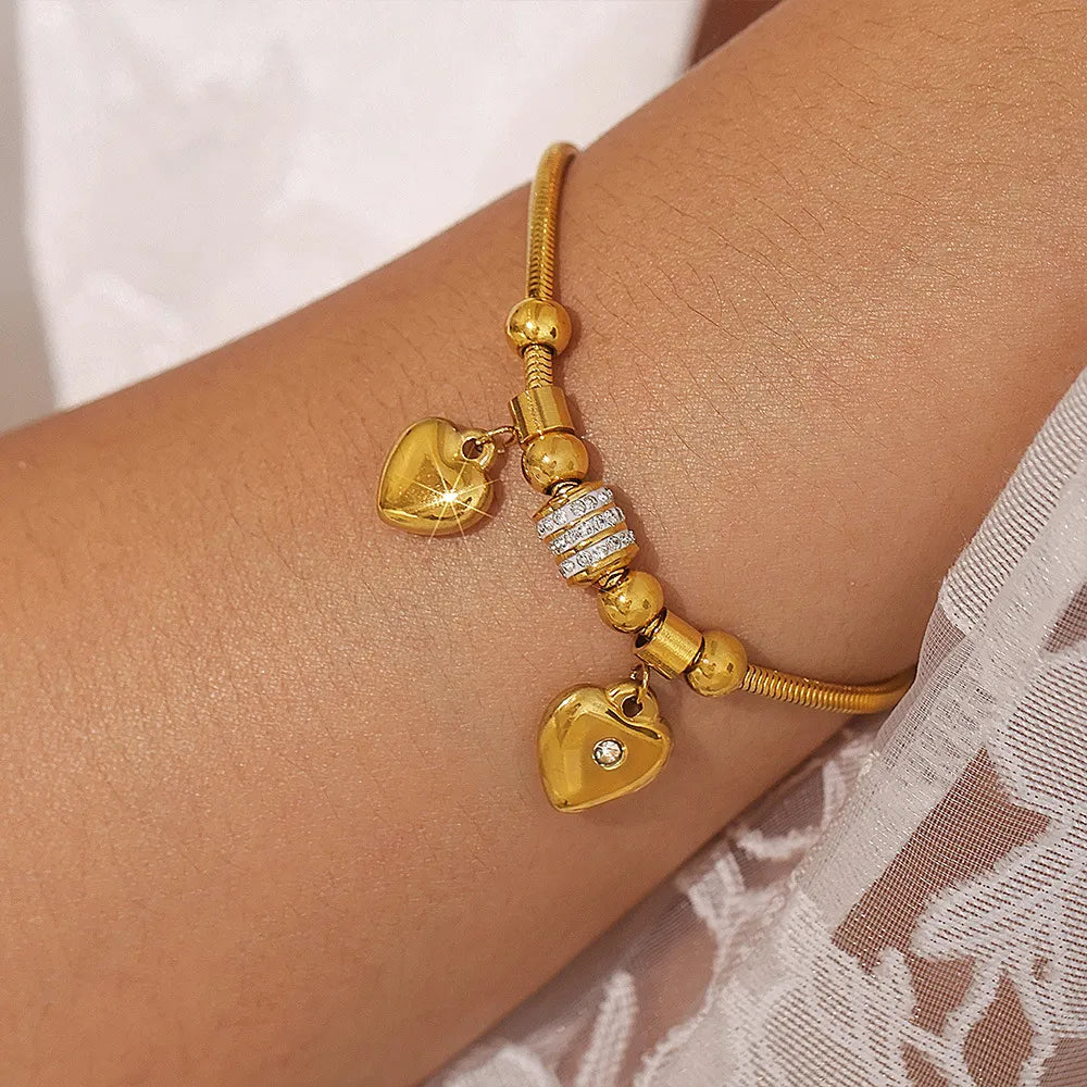 Gold charm bracelet with heart pendants and crystal accents
