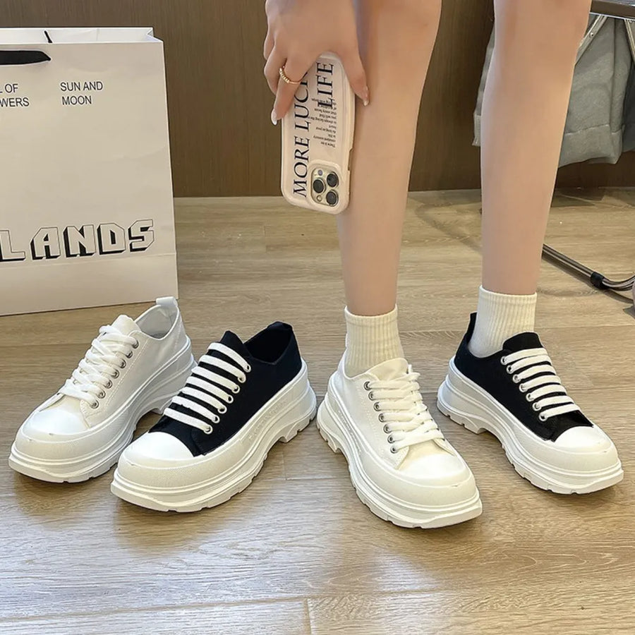 Chunky canvas platform lace-up sneakers in white and black with thick white soles.
