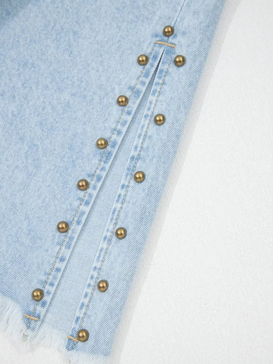 Light wash denim jeans with studded side slits and frayed hem detail.