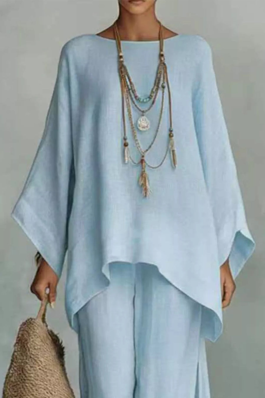 Light blue polyester two-piece set with flowing top and wide-leg pants, styled with layered necklace.