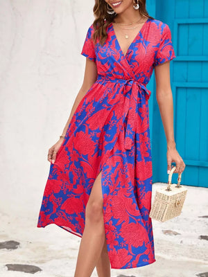 Wrap dress with red floral print on blue, v-neck, short sleeves, belted waist, and high slit.